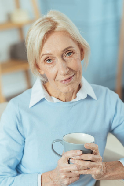 Pleasant senior lady feeling calm while drinking hot tea - Foto, Imagen