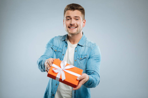 Positive delighted brunette male holding present - Foto, Imagen
