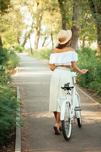 Una chica camina con una bicicleta por el callejón y mira a su alrededor
 - Foto, Imagen
