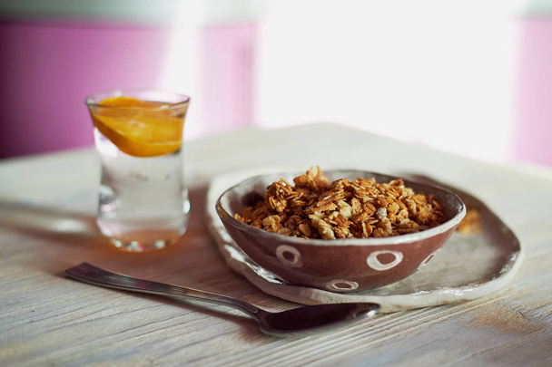 Healthy Breakfast of Champions. Muesli , a glass of water with a slice of orange.Ceramic handmade - Foto, afbeelding