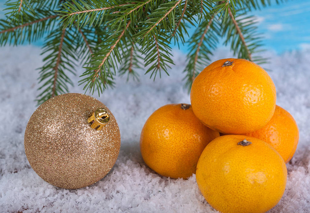 Mandarins and a Christmas ball in the snow under a spruce branch - Фото, зображення