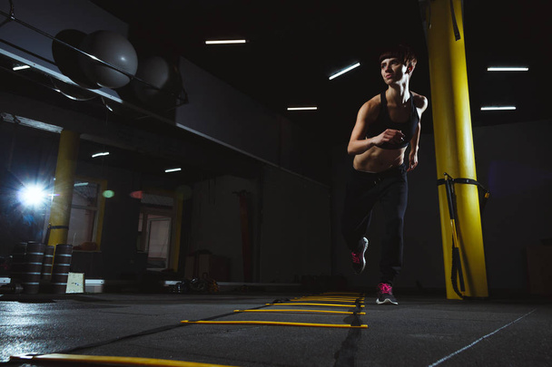 fitness girl doing crossfit exercises in gym in dark hall, sport - Foto, afbeelding
