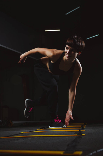 fitness girl doing crossfit exercises in gym in dark hall, sport - Photo, Image