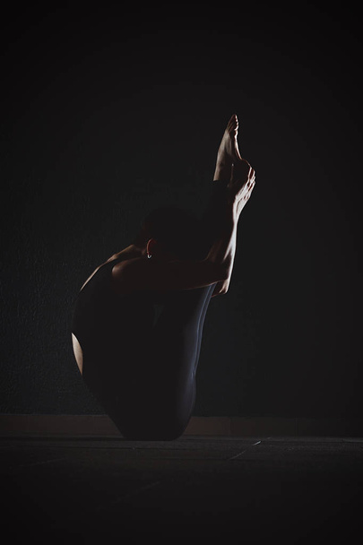 Fitness holka dělá crossfit cvičení v tělocvičně jóga pozice v tmavých h - Fotografie, Obrázek