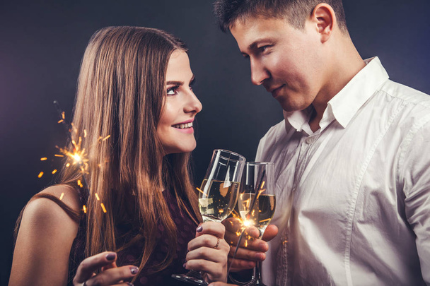 Pareja celebrando la víspera de Año Nuevo bebiendo champán e iluminando los bengalas
 - Foto, imagen