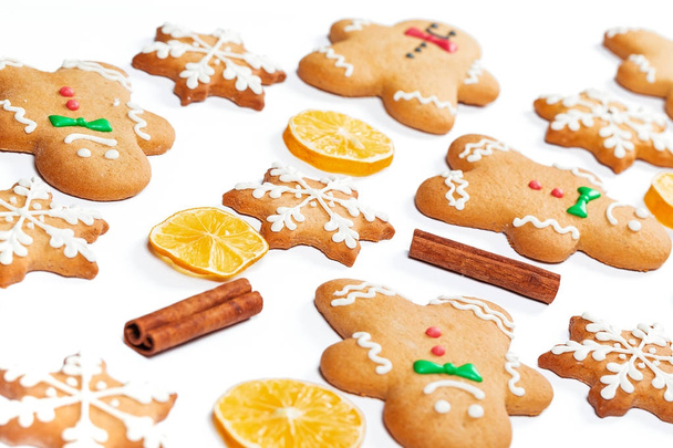 Karácsonyi mézeskalács férfiak és hópelyhek, citrom és fahéj botokkal fehér háttér. A szimbólum a téli ünnepek. - Fotó, kép