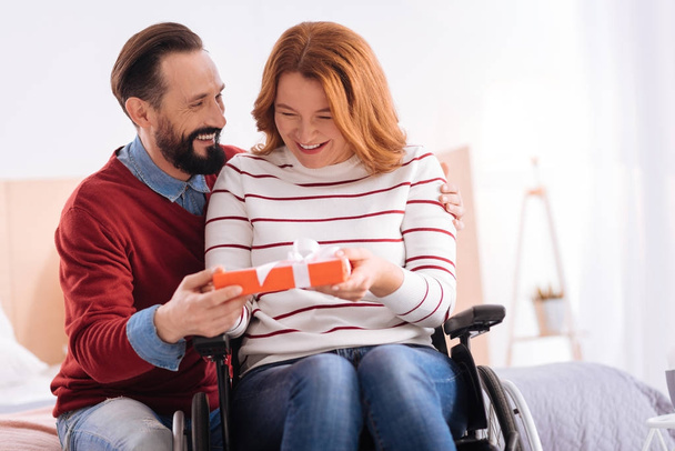 Hombre sonriente dando un regalo a una mujer discapacitada feliz
 - Foto, imagen
