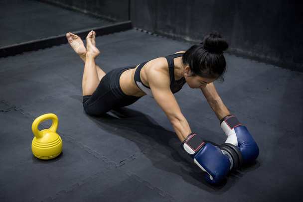 ダンベルを転がり運動を行う若いアジア ボクサー女性 - 写真・画像