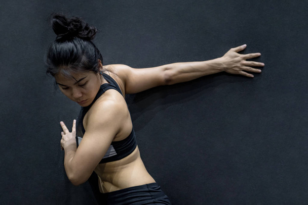 young asian woman stretching arm on black wall - Photo, Image