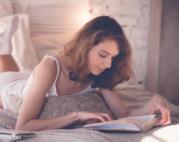 beautiful blond woman reading book in the bed. Relaxing concept - Valokuva, kuva