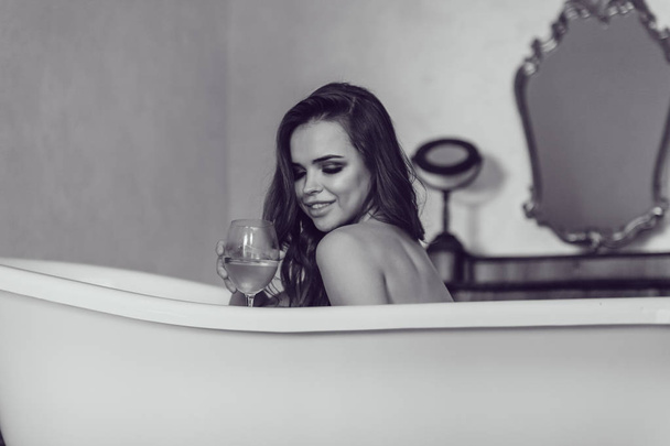 Beautiful sexy woman relaxed in the bath with a glass of wine. - Фото, зображення