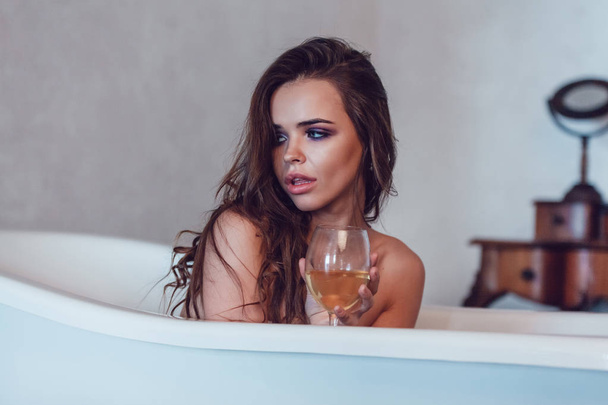Beautiful sexy woman relaxed in the bath with a glass of wine. - Photo, image