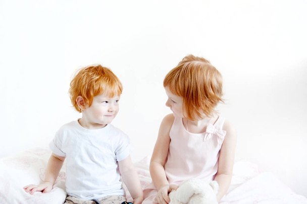 Red-haired brother and sister are sitting on the bed - Photo, Image