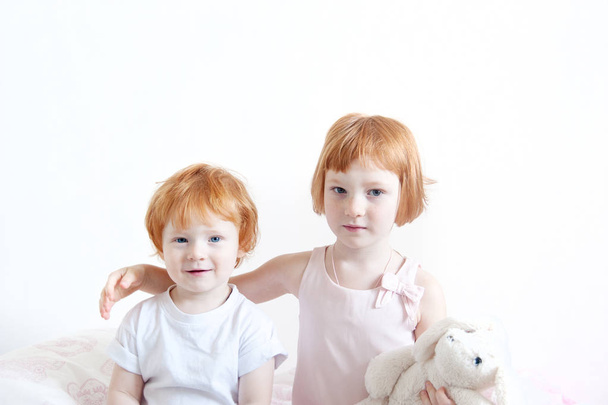Red-haired brother and sister embrace on the white background - Фото, изображение