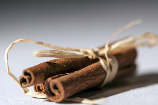 Close-up of cinnamon sticks bonded with ribbon knots. Shallow depth of field. - Фото, изображение
