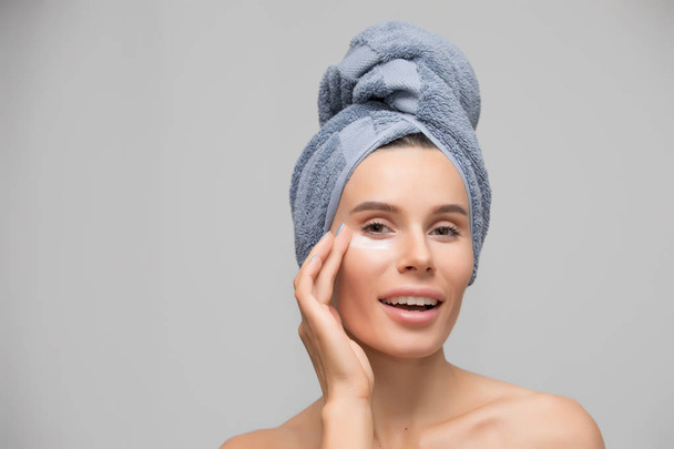 Beauty, woman apply moisturizing cream for skin under eye, isolated on grey - Foto, Imagem