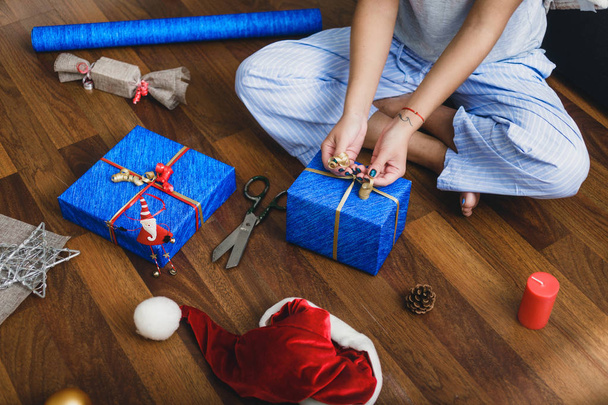 Woman sitting at home on the floor wraps Christmas gifts - Photo, Image