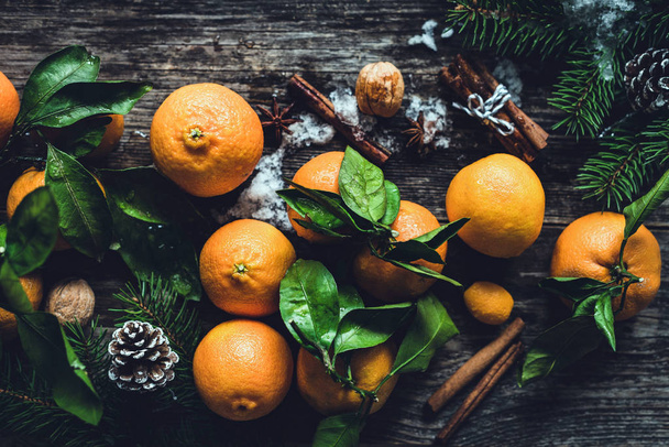 Tangerines, spices, pine cones and fir tree branches on wooden table. - Foto, afbeelding