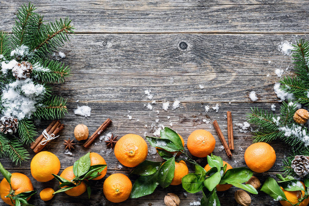 Tangerines, spices and fir tree on old wooden background. Traditional Christmas composition - Foto, Imagen