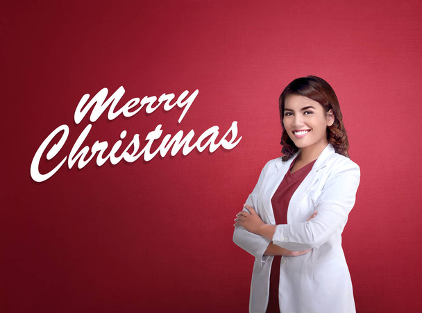 Beautiful asian business woman standing with Merry Christmas message on red background - Foto, Imagen