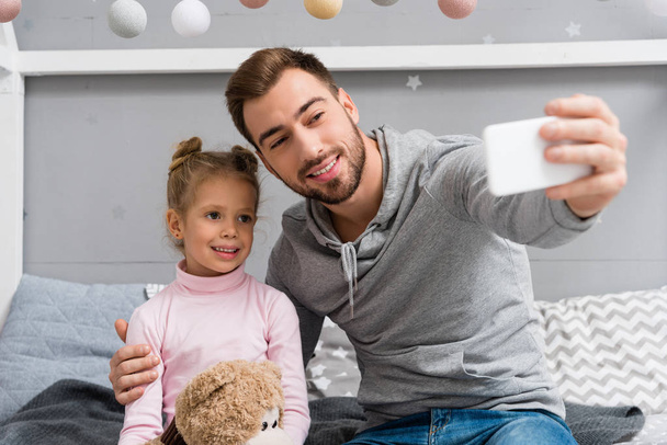 handsome young father and daughter with teddy bear taking selfie - Foto, immagini
