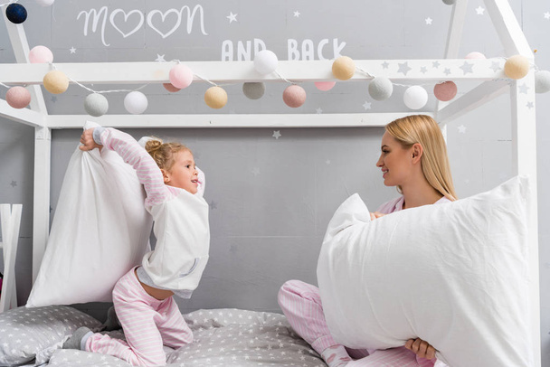mère heureuse et fille en pyjama se battant avec des oreillers
 - Photo, image