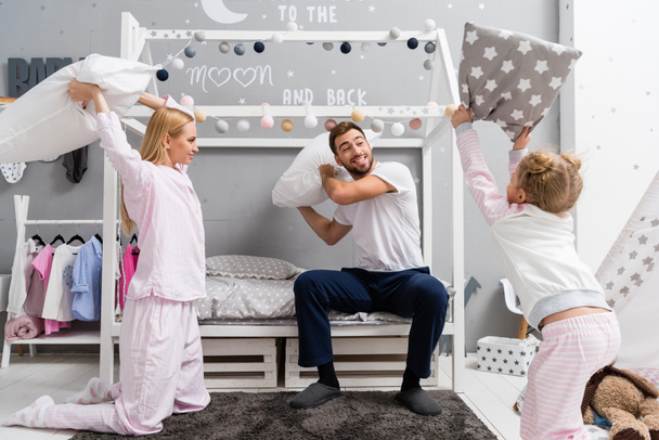 bela jovem família lutando com travesseiros no quarto de criança
 - Foto, Imagem