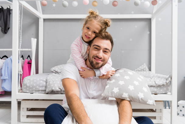 adorable daughter embracing father from behind in kid bedroom - Foto, afbeelding