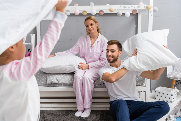 Szczęśliwa młoda rodzina walki z poduszki w sypialni dziecka - Zdjęcie, obraz