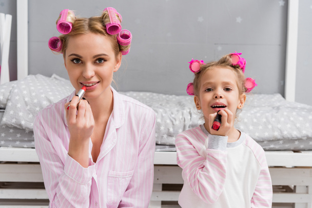 smiling mother and daughter doing makeup and looking at camera - Foto, imagen