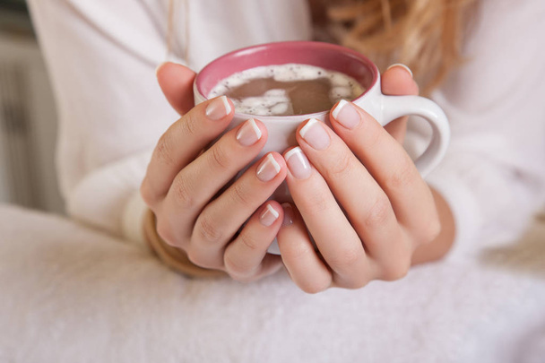 Closeup of coffee cup in female hands, blurred gentle background - Foto, Imagem