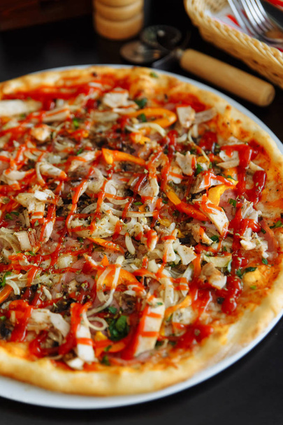 primo piano di pizza con pollo, pepe e salsa di pomodoro sul tavolo nero
 - Foto, immagini