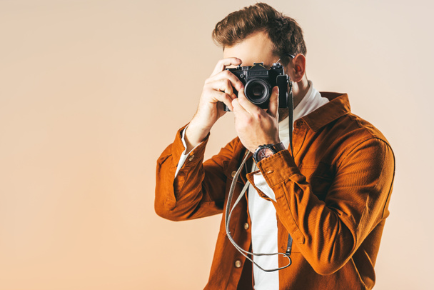 obscured view of fashionable man taking picture on photo camera isolated on beige - Fotoğraf, Görsel