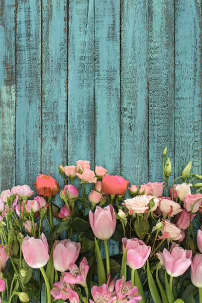 bovenaanzicht van mooie bloemen over groene houten achtergrond - Foto, afbeelding