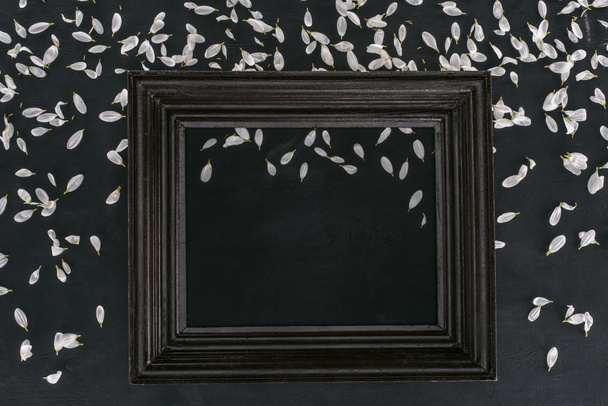 top view of vintage wooden frame with petals over black background - 写真・画像