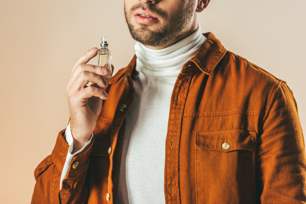 cropped shot of stylish man applying perfume isolated on beige - Foto, Imagem