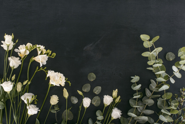 vista dall'alto di fiori di eustoma con foglie di eucalipto su sfondo nero
 - Foto, immagini