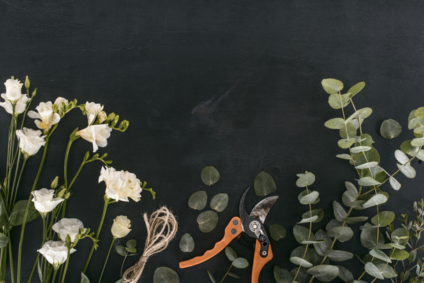 vue de dessus des fleurs d'eustomes avec des feuilles d'eucalyptus et des cisailles de jardin sur fond noir
 - Photo, image