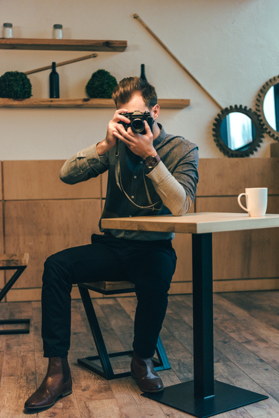Verdunkelte Sicht auf Mann, der in Café mit Fotokamera fotografiert - Foto, Bild