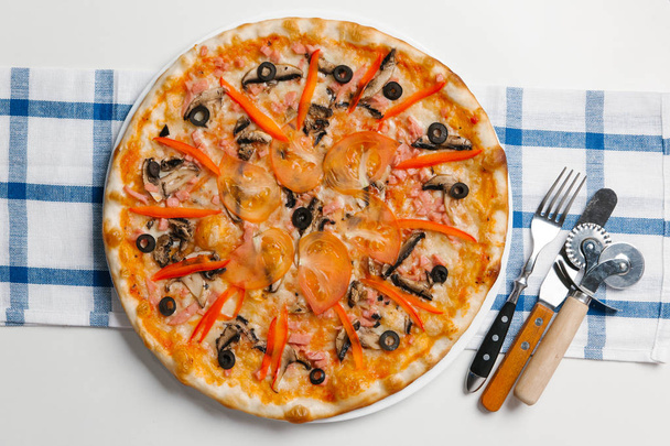 Pizza con cubiertos, cortador de pizza, espátula y servilleta a cuadros
 - Foto, Imagen