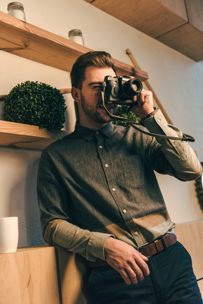 portrait of stylish man taking picture on photo camera in cafe - Фото, изображение