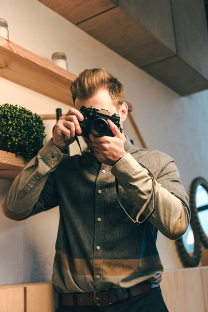 obscured view of stylish man taking picture on photo camera in cafe - Fotografie, Obrázek