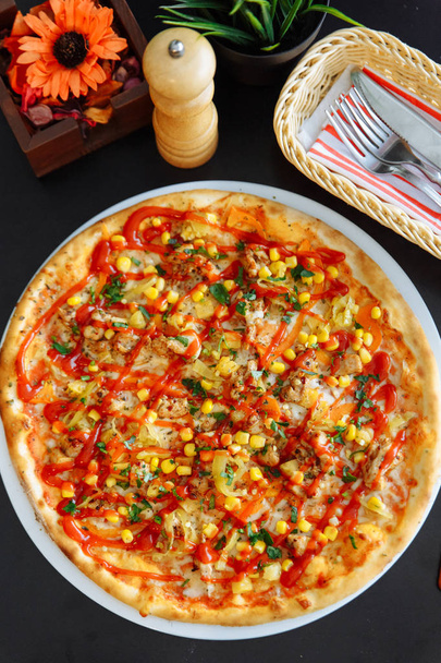bovenaanzicht van pizza met maïs zaden en tomaat saus op tafel zwart - Foto, afbeelding
