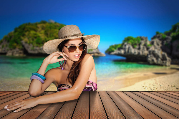 Beautiful brunette with straw hat and sunglasses in a tropical island background - Photo, Image