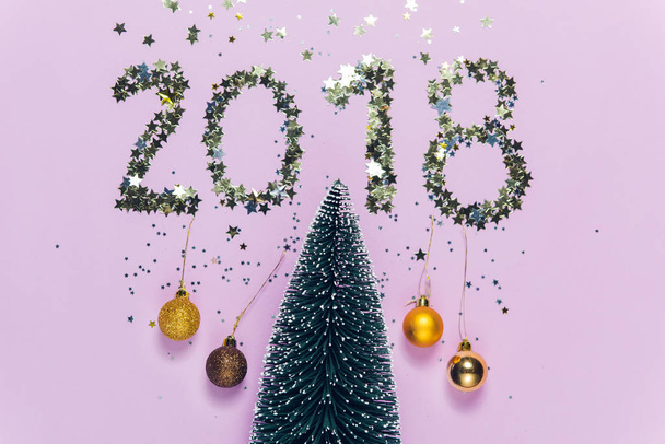 New Year 2018 writing composed of glittering confetti in the shape of stars over Christmas tree. New Year 2018 writing composed of glittering confetti over Christmas tree. - Photo, image