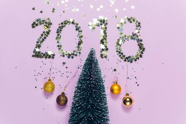 New Year 2018 writing composed of glittering confetti in the shape of stars over Christmas tree. New Year 2018 writing composed of glittering confetti over Christmas tree. - Foto, Imagem