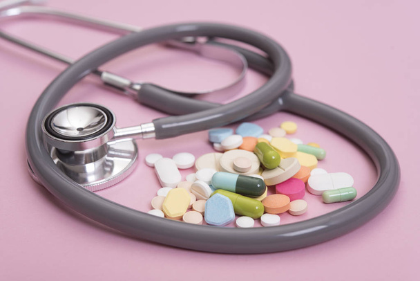 Stethoscope and colorful medicine. Pharmacy on pink background. - Φωτογραφία, εικόνα