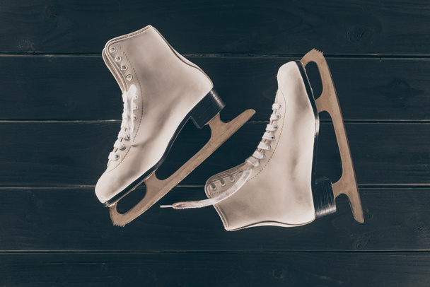 vista superior de par de patines blancos sobre superficie de madera rayada
 - Foto, imagen