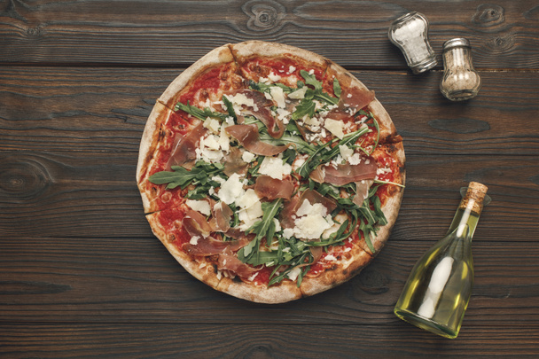vista superior de pizza caseira, azeite e especiarias em mesa de madeira
  - Foto, Imagem