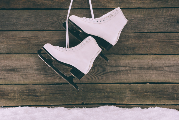 pair of white skates hanging on wooden wall with shoelaces - 写真・画像